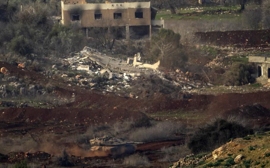 An Israeli tank seen near the bottom third of the photo, while the middle third shows the rubble of a destroyed building.