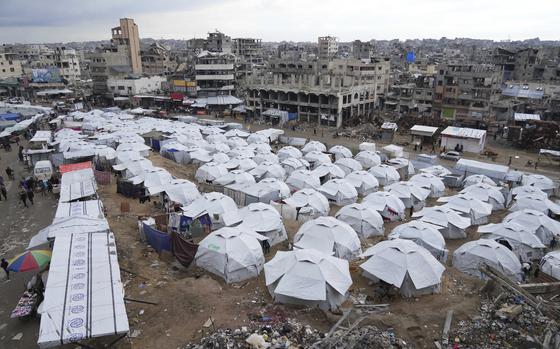 A sprawling tent camp for displaced Palestinians sits adjacent to destroyed homes and buildings in Gaza City, Gaza Strip, Saturday, March 1, 2025 during the Muslim holy month of Ramadan. (AP Photo/Abdel Kareem Hana)