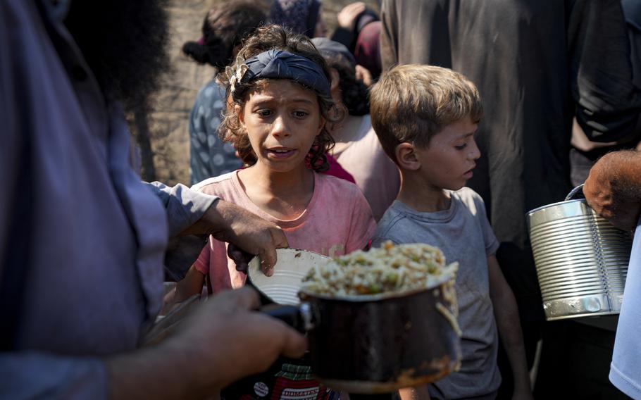 Palestinians line up for food distribution in Deir al-Balah, Gaza Strip