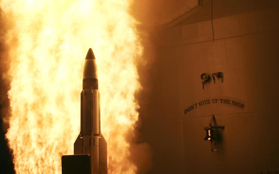 Fire flares around a missile being launched from the USS Lake Erie.