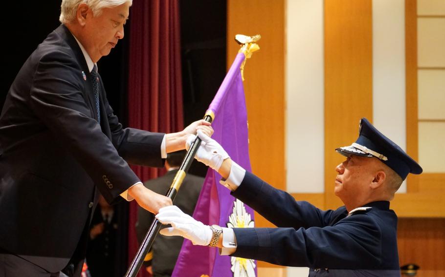 Japan’s defense minister passes a new command flag to a general during a formal activation ceremony.