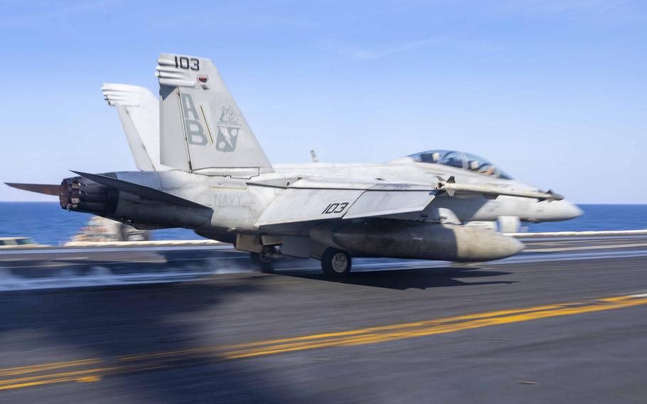 A Navy fighter jet begins its takeoff run on an aircraft carrier.