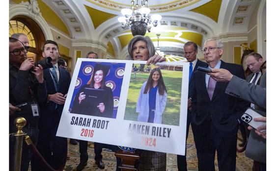 Sen. Joni Ernst, R-Iowa, holds a poster with photos of murder victims ...