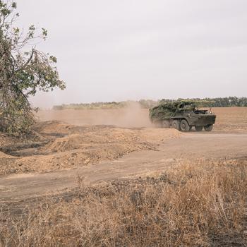 An armored vehicle kicks up dust.