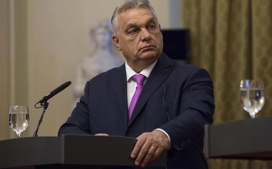 A man in a suit by a podium looks to the side to something off-camera.