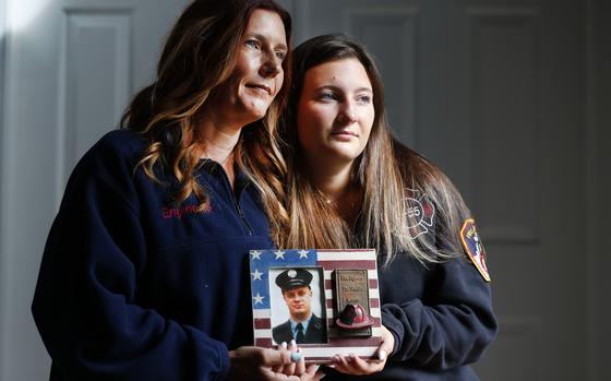 Pamela Yarosz and her daughter Capri are shown with a photo of New York firefighter Christopher Michael Mozzillo Saturday, Sept. 7, 2024, in Freehold, N.J.. Mozzillo, who died in the 9/11 attacks, was Pamela's brother. (AP Photo/Noah K. Murray)