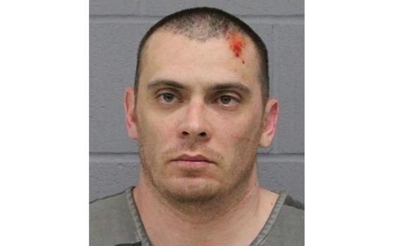 Police booking photo of a former Army officer with close-shaved dark hair and a wound on his forehead.