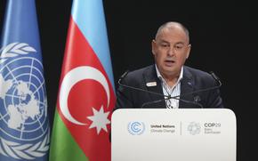 A man in a suit stands and speaks at a podium with the United Nations insignia.