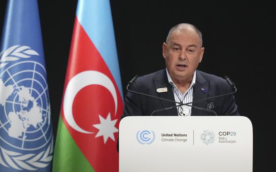 A man in a suit stands and speaks at a podium with the United Nations insignia.