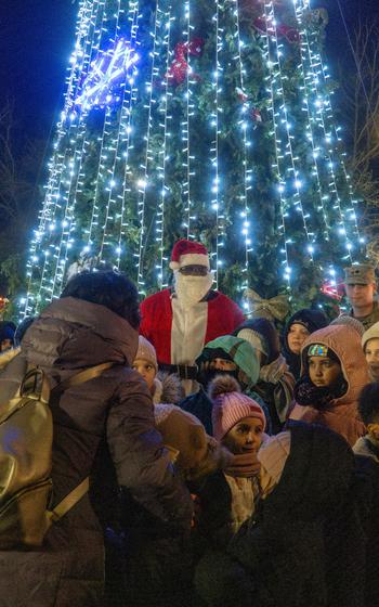 Santa Claus stands in front of the lit Christmas tree at Mihail Kogălniceanu Air Base, Romania.