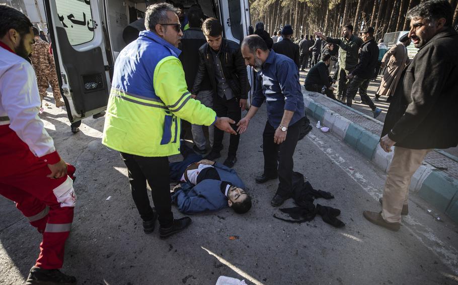 People stay next to an injured man after an explosion in Kerman, Iran, Wednesday, Jan. 3, 2024. Explosions at an event honoring a prominent Iranian general slain in a U.S. airstrike in 2020 have killed at least 73 people and wounded over 170 others, state-run media in Iran reported Wednesday.