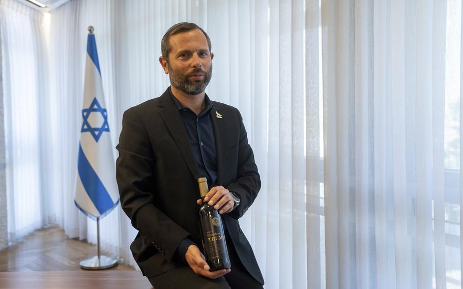 The leader of a pro-West Bank settlement group holds a bottle of wine that is named for U.S. President-elect Donald Trump.