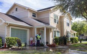 A maintenance worker in 2019 for Balfour Beatty Communities, a private company that manages military housing, power washes the driveway of a home at Marsh Cove, a military residential community at Naval Station Mayport, Fla.