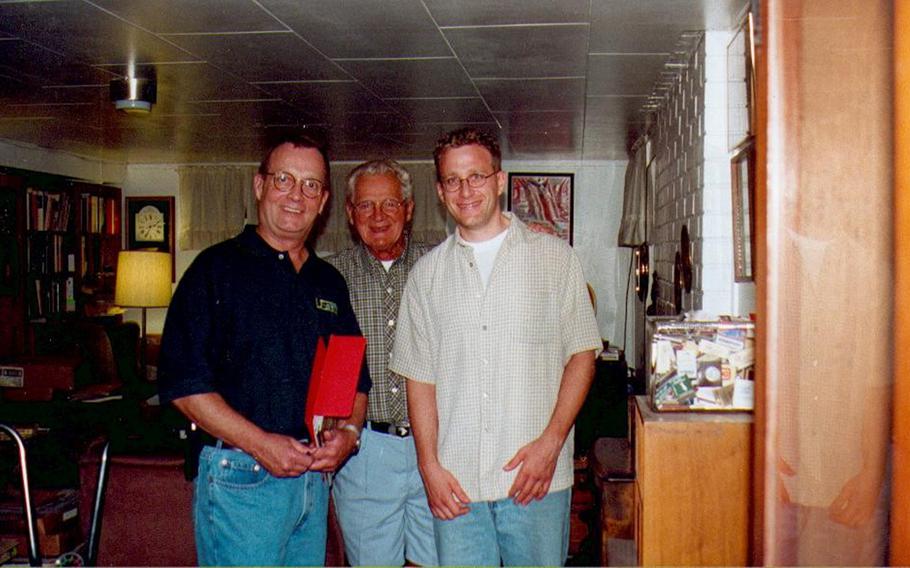 Three men pose for a photo in an office.