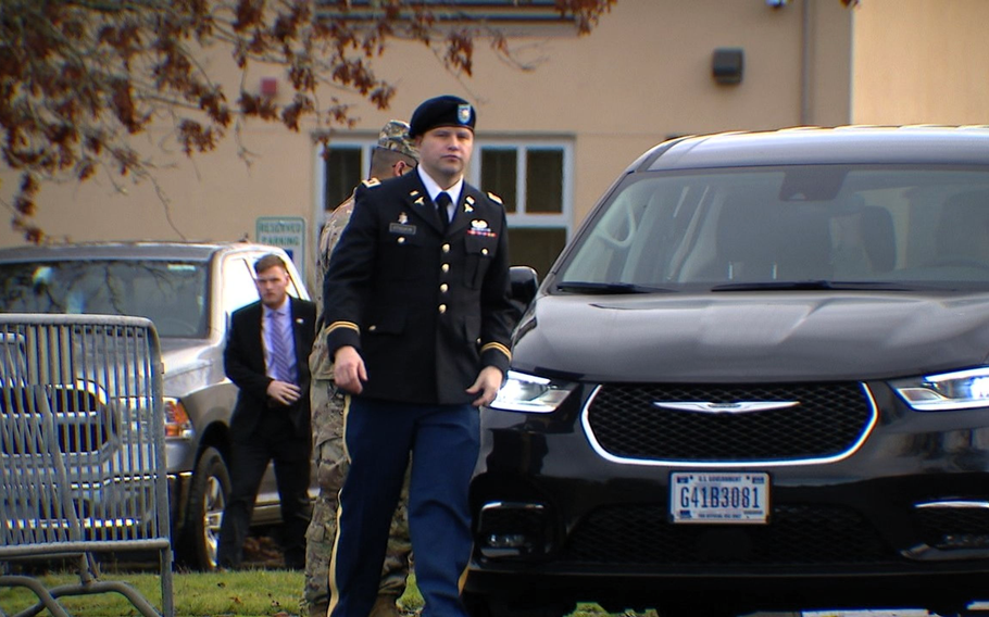 Stockin in uniform walking in front of a car.