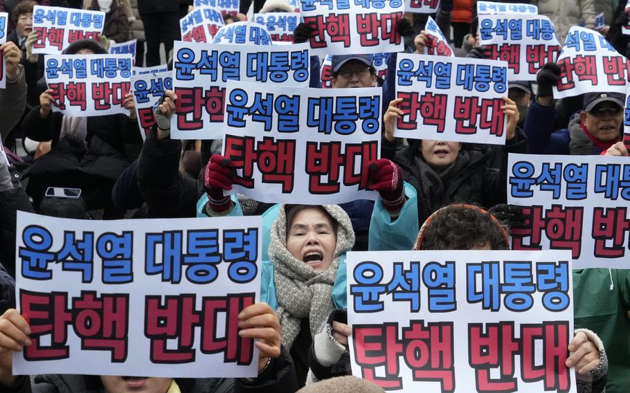 Supporters for impeached South Korean President Yoon Suk Yeol hold signs during a rally in Seoul.