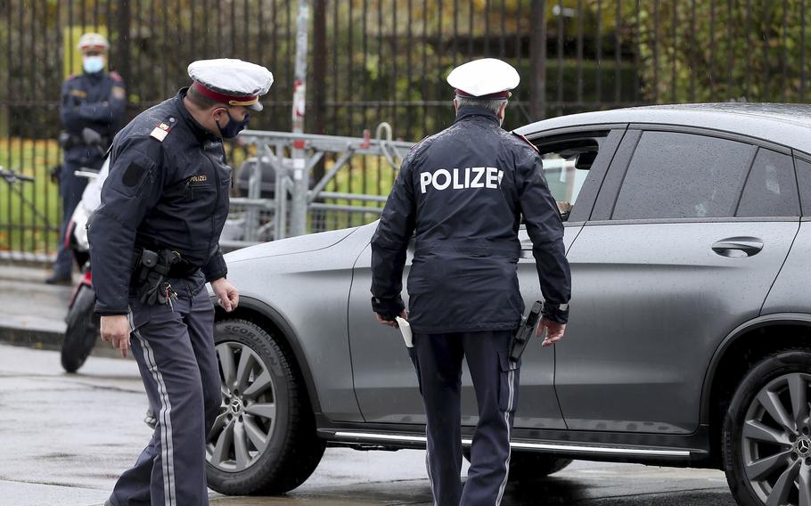 Police officers check a car in downtown Vienna, Austria, Friday, Oct. 30, 2020.