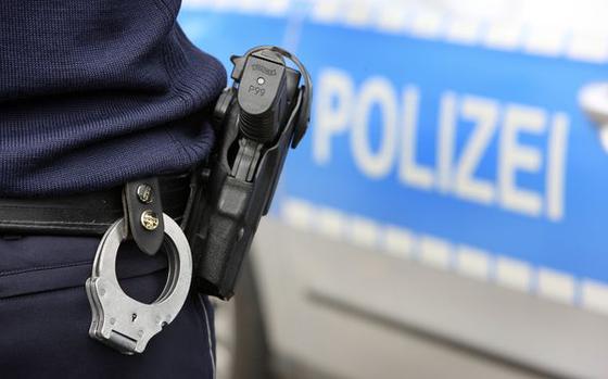 Polizei, Streifenwagen.Polizist mit Handschellen und Dienstwaffe, Walther P99, im Holster. Symbolbild.