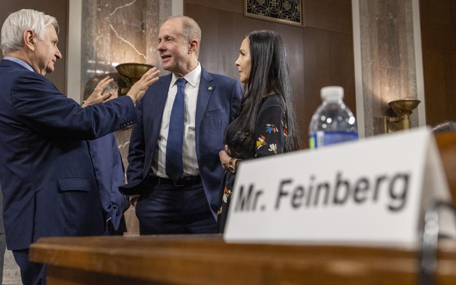 Three people standing and chatting at a hearing.