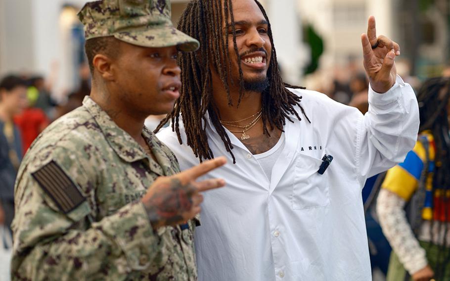 Social media food influencer Keith Lee makes a peace sign with his fingers as he poses for a picture with a U.S. sailor at Yokosuka Naval Base, Japan.