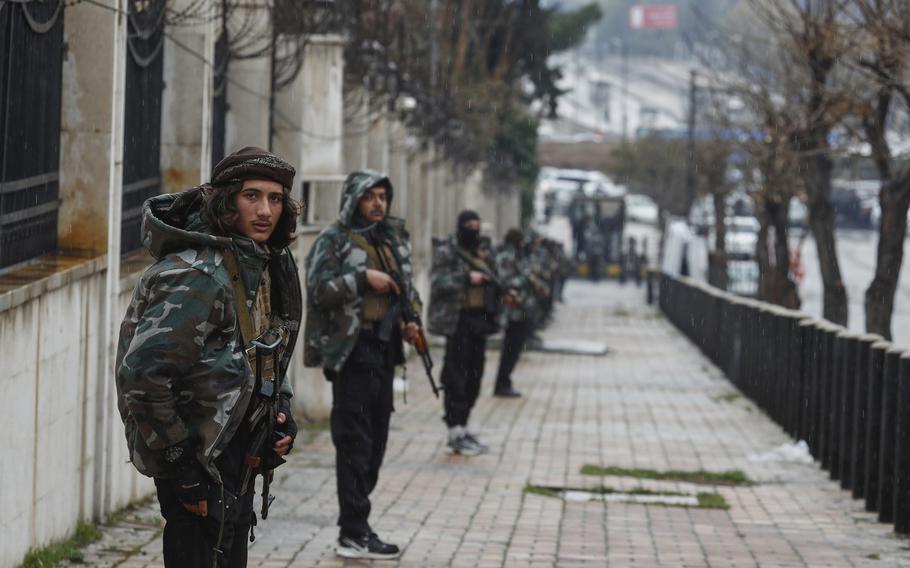 Syrian soldiers stand on a street.