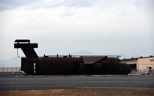 The fire training area at Yokota Air Base, Japan, includes a rusting aircraft mockup, a tower and a few wrecked cars parked west of the runway.