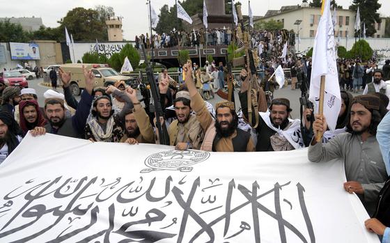 FILE - Taliban fighters hold their flag as they celebrate one year since they seized the Afghan capital, Kabul, in front of the U.S. Embassy in Kabul, Afghanistan, Monday, Aug. 15, 2022. (AP Photo/Ebrahim Noroozi, File)