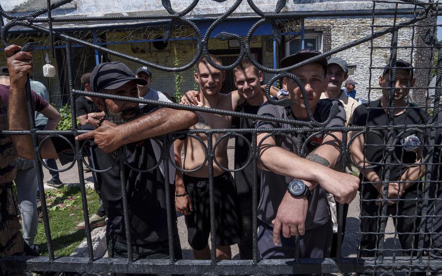Prisoners stand behind the fence in the yard at a prison in the Dnipropetrovsk region of Ukraine on June 21, 2024.