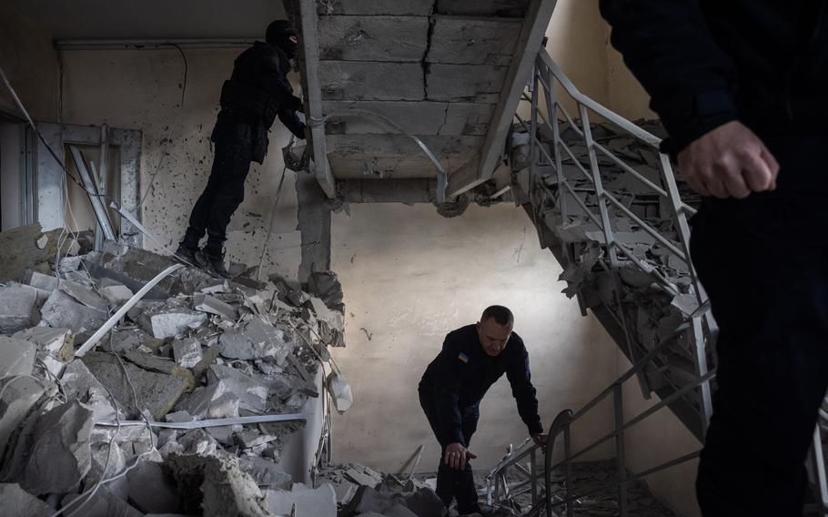 Emergency workers go through a damaged residential building in Kharkiv’s city center on Tuesday. 