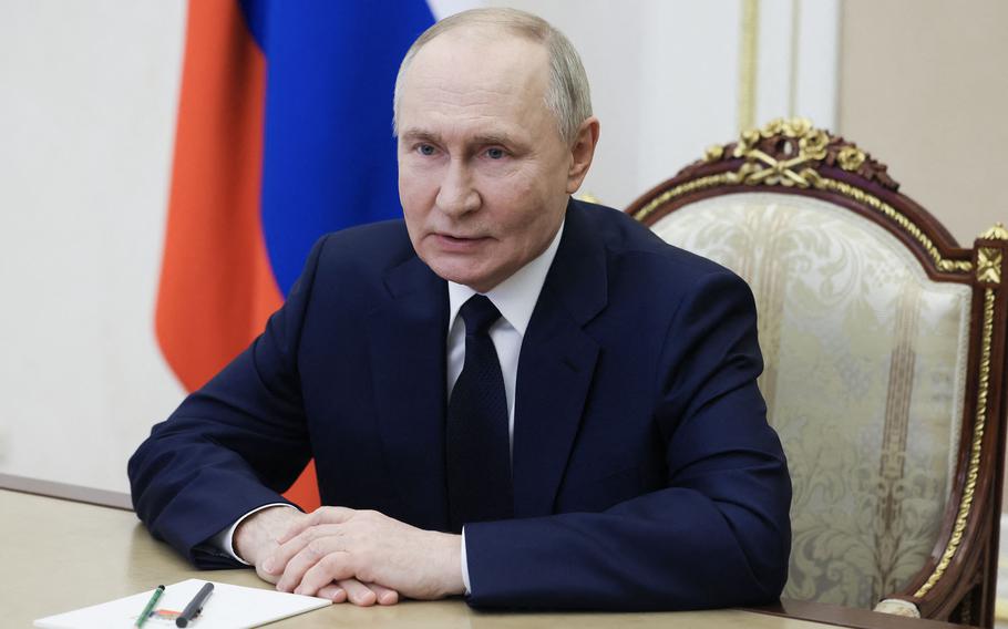 Vladimir Putin speaks with his hands folded on a desk.