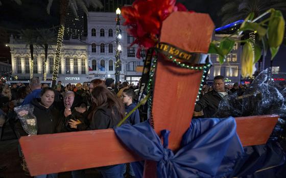 Jessica Perez, holding flowers left, hugs her mother Martha Perez who cries out by a cross memorializing her daughter, Nicole Perez, who was a victim on the New Year's Day attack, on Canal Street near the intersection of Bourbon Street in New Orleans, Saturday, Jan. 4, 2025. (AP Photo/Matthew Hinton)