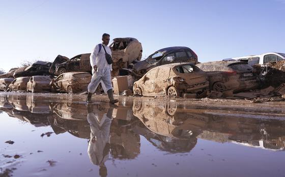 FILE - A man walks past stacked up cars after floods in Catarroja that left hundreds dead or missing in the Valencia region in Spain, Nov. 12, 2024. (AP Photo/Alberto Saiz, file)