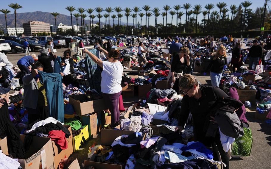 People survey boxes of clothes in a wide open area on a sunny day.