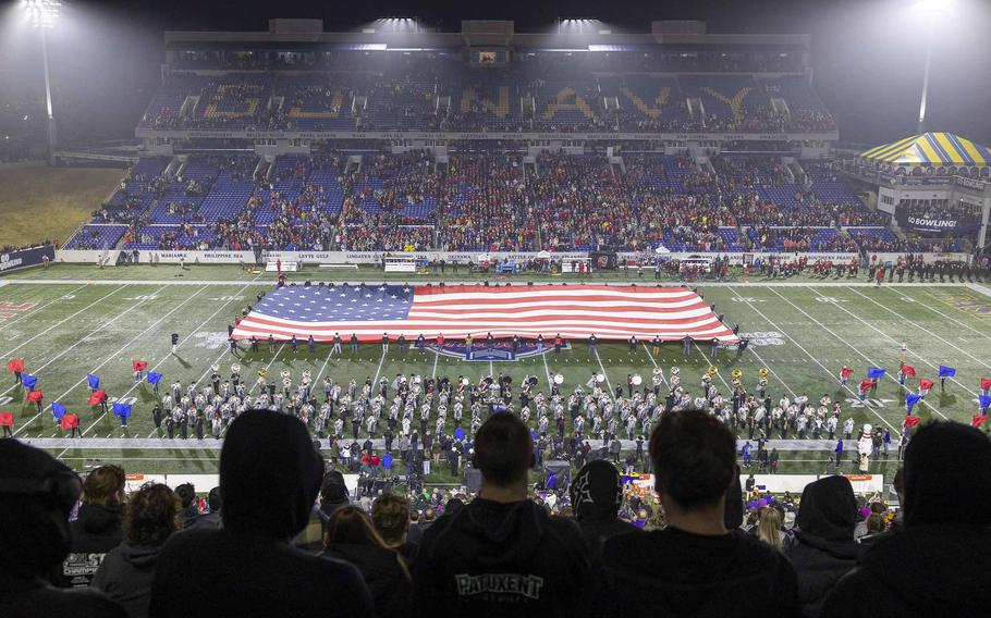 People hold up a giant American flag on a football field.