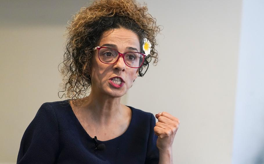 A woman with red-framed glasses conducts an interview.