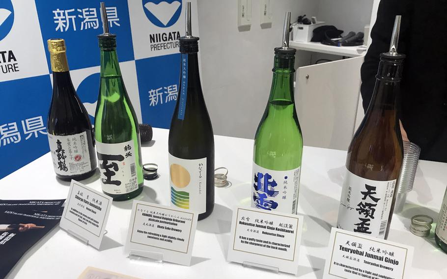 Various bottles with kanji writing on their labels and explanatory cards in front of them are displayed on a table.