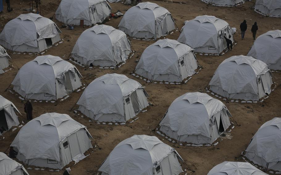 Rows of white tents erected in a desert setting.