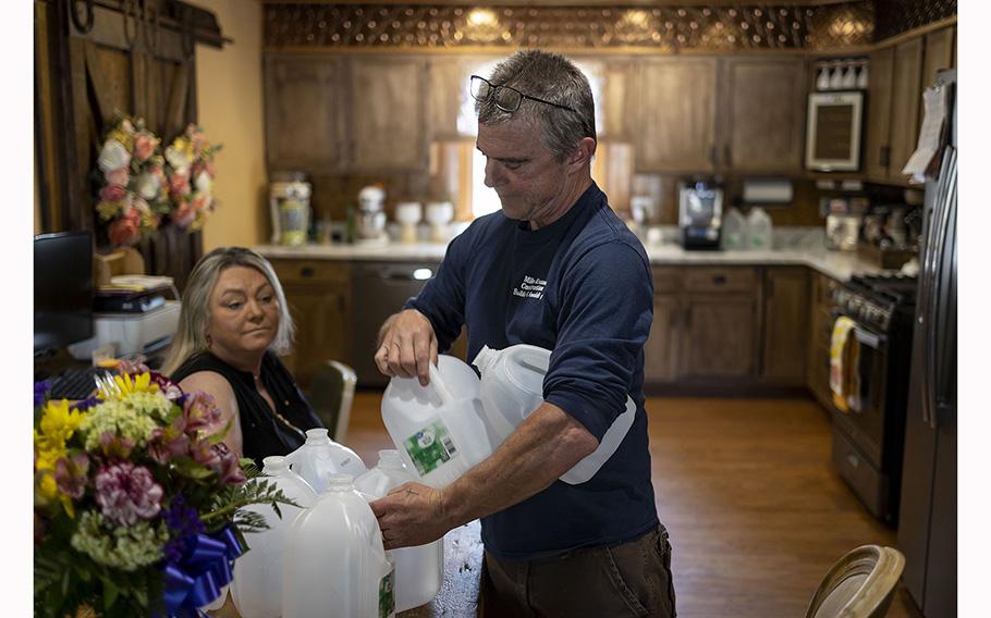 Mike Krause picks up some of the empty jugs he and his wife Kacy buy for drinking water, June 22, 2023, in Rockton. The Krauses, who live near the site of the 2021 Chemtool factory fire, now drink only bottled water after testing of their well water found toxic chemicals. 