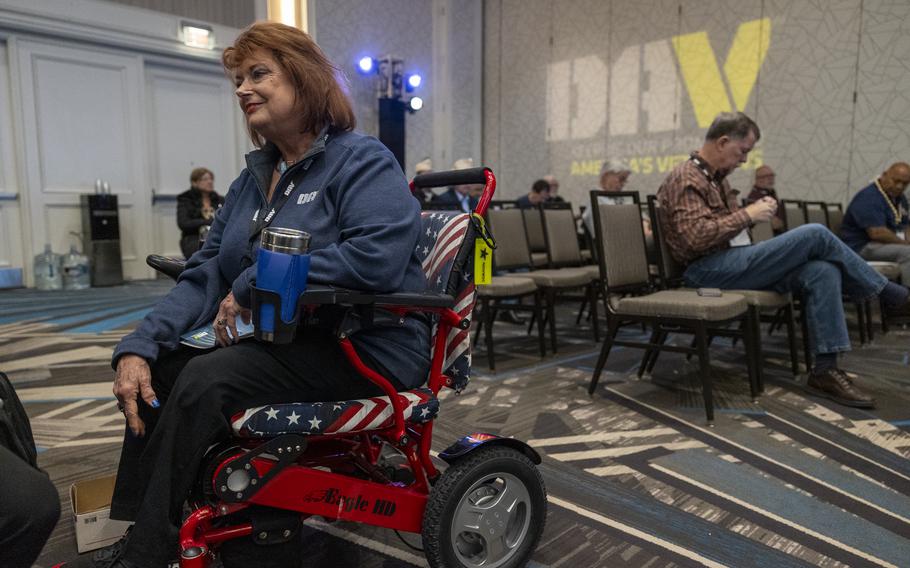 A woman sitting in a wheelchair with red, white and blue cushions.