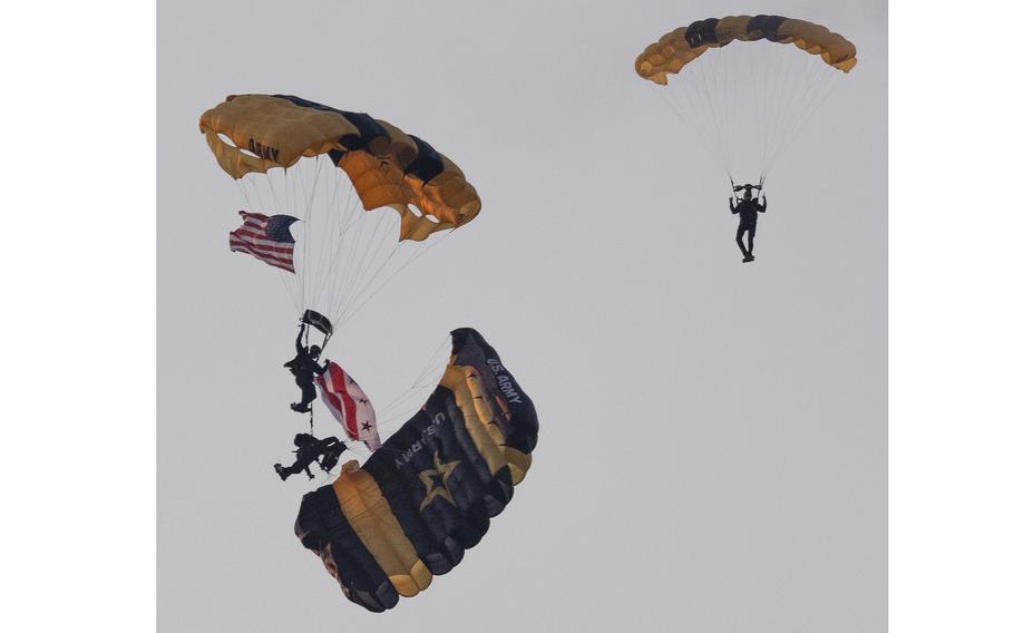 Army soldiers parachuting from the sky with American flag and U.S. Army parachutes