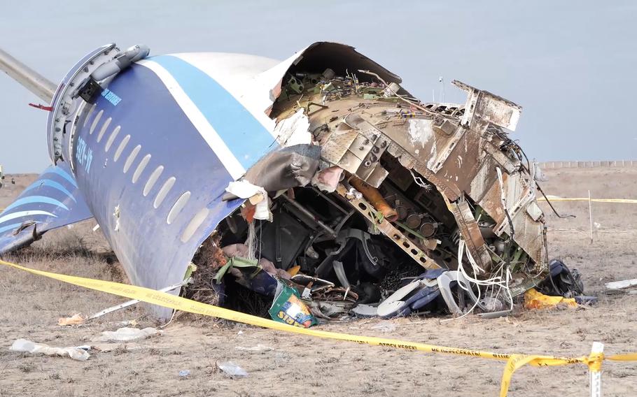 The wreckage of part of an airplane is seen on the ground, with the hull ripped open.