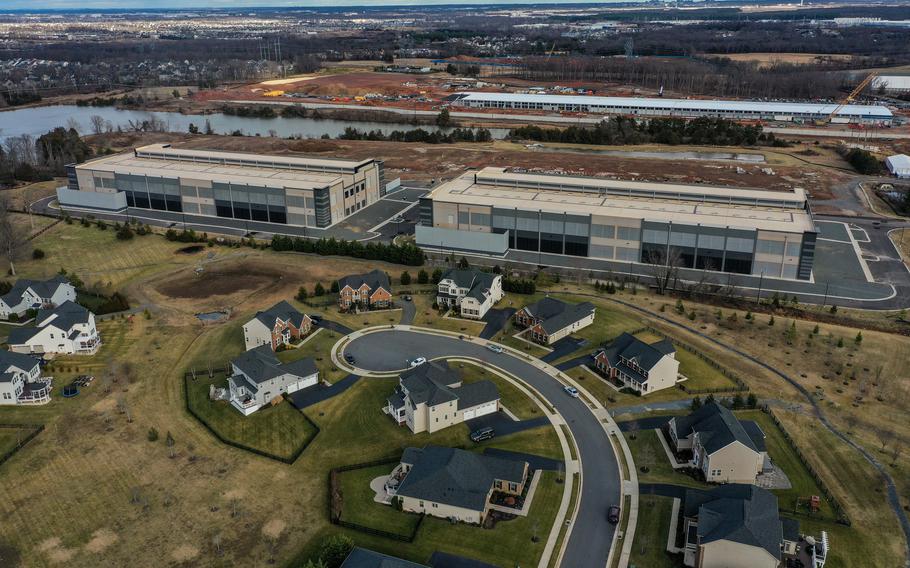 Data centers loom large close behind a cluster of houses in a residential subdivision.