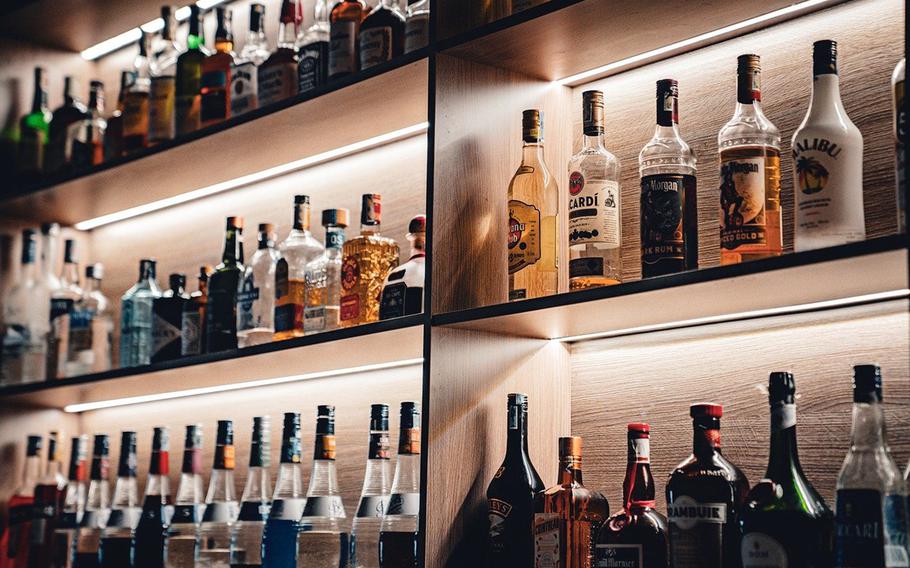 Bottles of alchohol line a shelf.