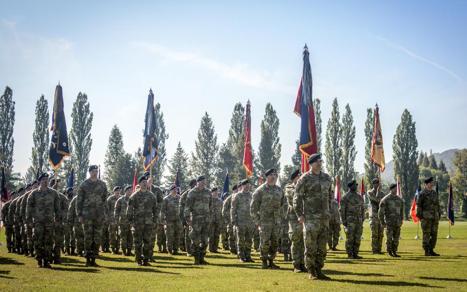 Soldiers stand in formation with trees and a blue sky in the background at Camp Casey.