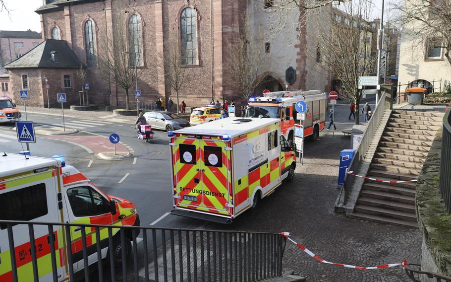 Rescue vehicles parked by a sidewalk near stone buildings.