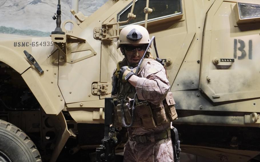 A cast figure of Retired Maj. David McGrath positioned next to an M-ATV vehicle at the National Museum of the Marine Corps.