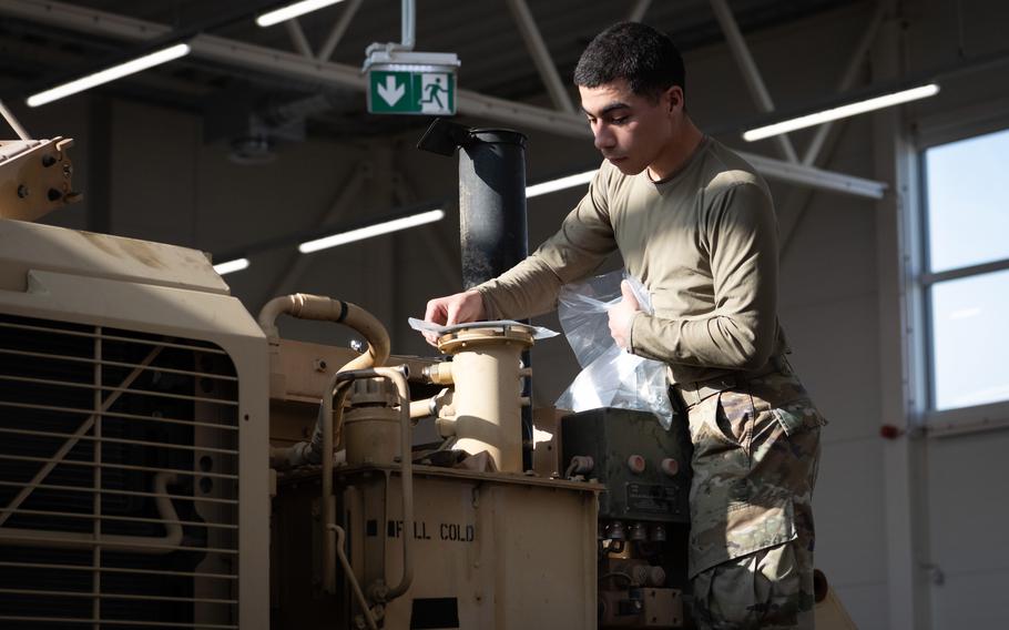 A soldier works on a vehicle.