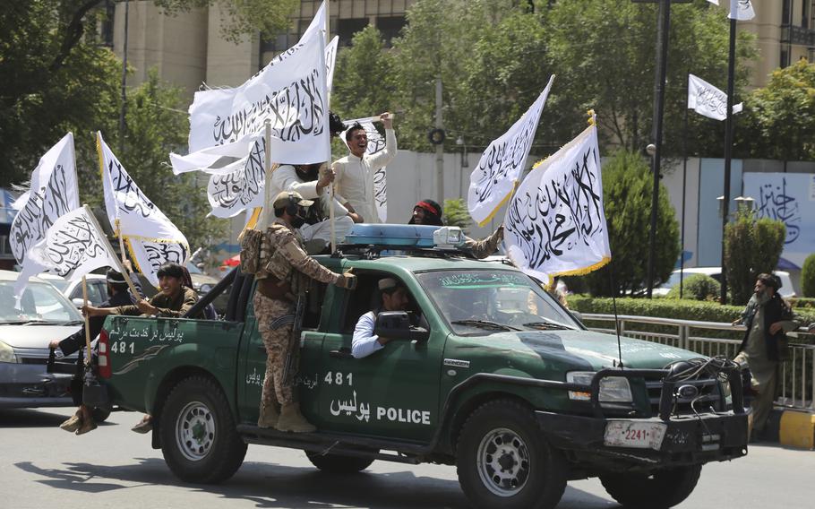 Taliban fighters ride in a car with flags, as part of a celebration of the third anniversary of the U.S. withdrawal from Afghanistan, Aug. 14, 2024.