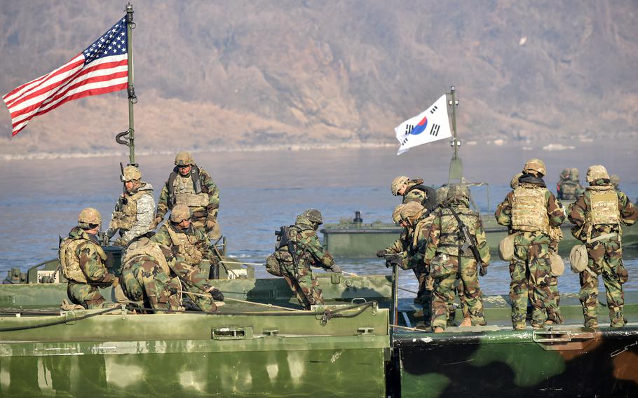 An American flag and a South Korean flag fly as soldiers undertake a wet-gap crossing.