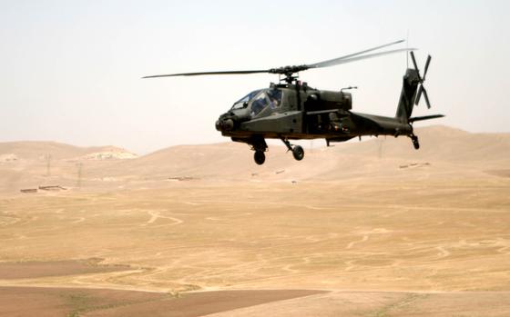 An Apache helicopter flies over the desert terrain between Tall'Afar ...